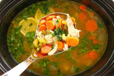 Crockpot Lemon Chicken Orzo Soup in a slow cooker and spoon.