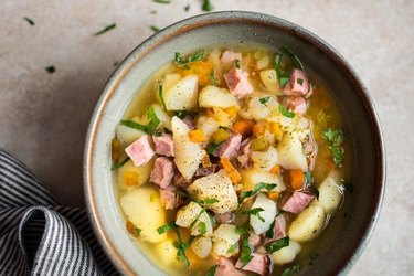 Slow Cooker Ham and Potato Soup in a gray bowl on brown countertop