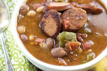 Slow Cooker Cajun Sausage and Bean Soup in white bowl on table.