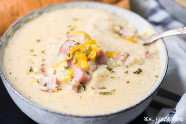 Slow Cooker Ham and Potato Cheese Soup in a gray bowl on table.