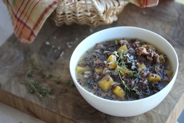 A white bowl of Turkey Sausage, Squash and Quinoa Soup on a wooden table