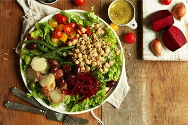 Vegan Nicoise Salad in large white plate on wooden table.