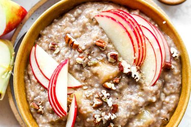 Close up of apple pie steel cut oats topped with chopped pecans and red apple slices