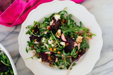 Roasted Beet Salad With Goat Cheese and Pistachios in a white bowl over marble countertop.