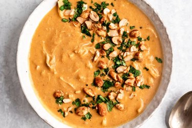 Slow Cooker Pumpkin Peanut Butter Chicken Soup in a white scalloped bowl on marble countertop.