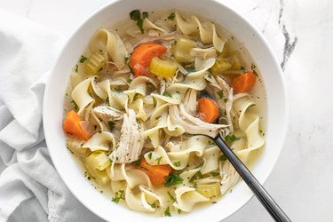 Slow Cooker Chicken Noodle Soup in a slow cooker on marble countertop.