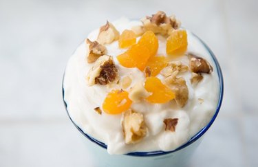 Trail Mix Almond Yogurt Parfait in a glass in front of a white background