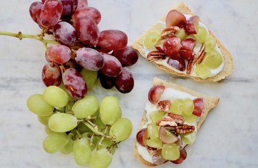 Grape bruschetta with bunches of red and green grapes on white marbled background