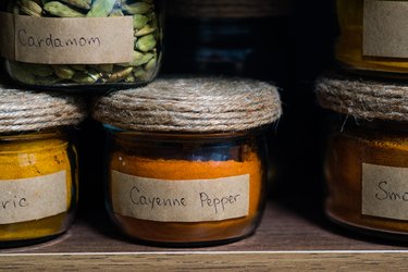 a glass jar of cayenne pepper on a shelf with other spices