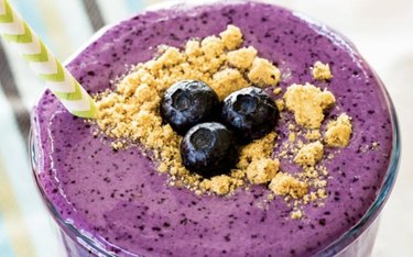 Blueberry Cheesecake Protein Smoothie in a Glass Garnished With Blueberries and Graham Crackers