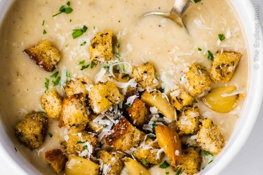 a close up overhead photo of creamy garlic soup with croutons