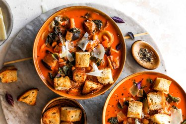 Two bowls of Roasted Eggplant Soup with croutons. on a gray marble serving platter