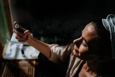 overhead view of a person with brown hair in their bathroom using magnesium spray for sleep