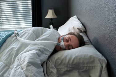 a person sleeping in bed wearing a CPAP machine