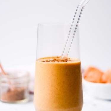 a close up of a glass of a sweet potato smoothie with a clear straw