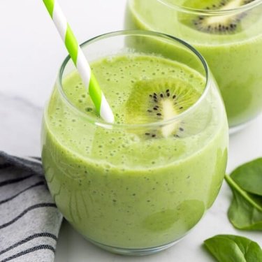 a close up of a glass of kiwi smoothie with a green striped straw