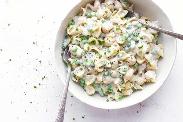 Mac and cheese and peas in a white bowl