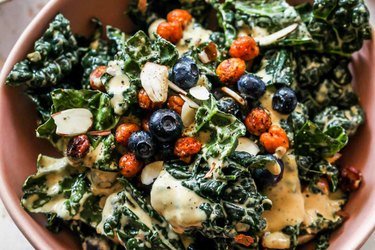 Blueberry kale caesar salad with smoky chickpeas in a pink bowl