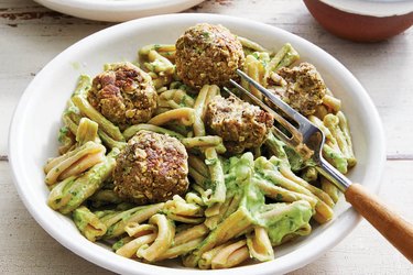 Gemelli pasta with zucchini meatballs and avocado chimichurri in a white bowl with fork