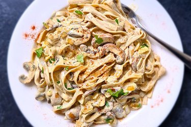 Creamy mushroom pasta on a white plate with a fork