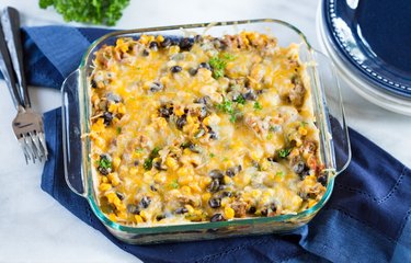 High Protein Vegetarian Tortilla Casserole in a clear dish on a dark blue napkin with forks