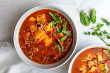 A vibrant tomato-based soup with ravioli and beef