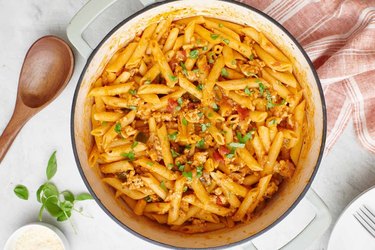 A large pot of penne doused in sauce and turkey