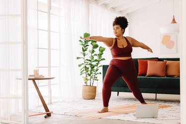 Person in athletic clothing doing yoga in living room to represent best types of exercises for fibromyalgia.
