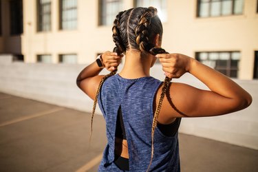 Rear view of person wearing braids as example of one of the best workout hairstyles getting ready to work out outside