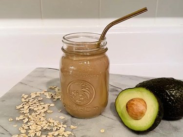 Chocolate Avocado Smoothie in a mason jar next to cut avocado on kitchen countertop