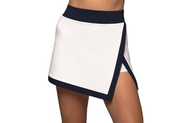 Model, shown from the waist down, wearing a white Michi brand tennis skirt with black trim