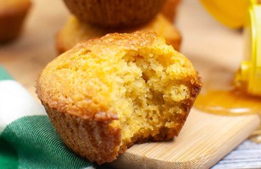 A closeup of a golden brown cornbread muffin with a bite taken out of it.