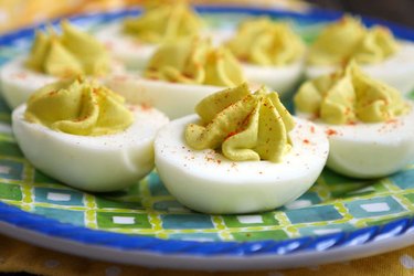Avocado deviled eggs recipe made with avocado instead of mayo on a blue plate.