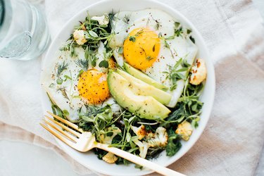 Eggs greens and avocado breakfast bowl recipe in a white bowl on tablecloth