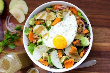 Avocado breakfast salad with greens, root veggies and an egg on top.