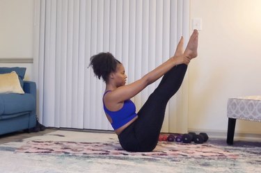 Pilates instructor demonstrates how to do the open leg rocker while at home in living room