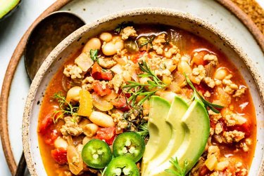 Buffalo Chicken Chili in a bowl with avocado and jalapeños on top.