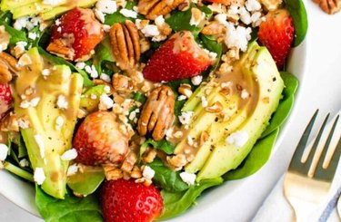 Strawberry Salad With Balsamic Vinaigrette with avocado, pecans and greens next to a silver fork