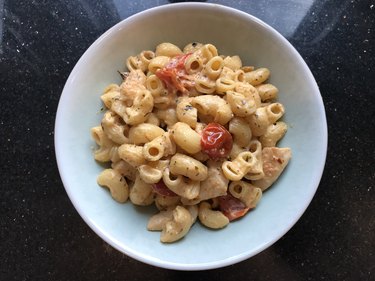 一个开销的照片白碗意大利面用Boursin奶酪,鸡肉和西红柿