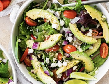 A salad with avocados, onions, tomatoes and other guacamole ingredients