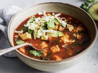 A bowl of Mexican tortilla soup with sliced avocado as a topping