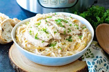 Bowl of linguine noodles topped with chicken strips and parmesan cheese in alfredo sauce.