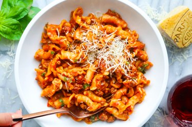 Pasta with ground beef in tomato sauce on a white plate on marble background