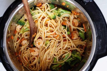 Instant Pot filled with lo mein noodles, broccoli, carrots, and shrimp.