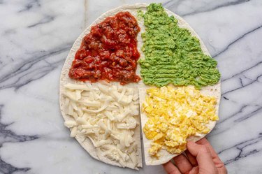 Breakfast tortilla wrap with avocado, salsa cheese and eggs
