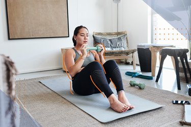 Woman doing a dumbbell ab workout in her living room