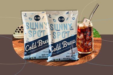 Grounds & Hounds Cold Brew Coffee Kit with two bags and a mason jar with cold brew coffee and ice on wooden tabletop