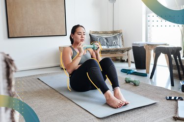person doing a dumbbell ab workout in her living room