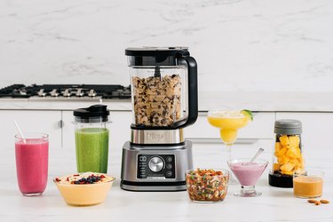 Ninja blender with cookie dough in it with smoothies and drinks on the side