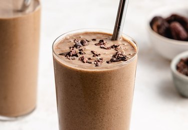 Coffee Protein Smoothie in a glass with a silver straw and cacao nibs